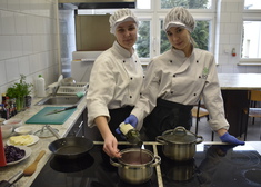 Dwie dziewczyny ubrane w stroje kulinarne, przyrządzające posiłek