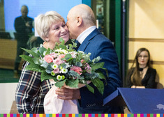 Mężczyzna całuje kobietę trzymając w dłoni bukiet kwiatów