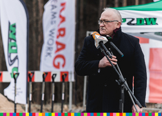 Józef Zajkowski, wójt gminy Sokoły przemawia do zebranych i stoi na tle flag
