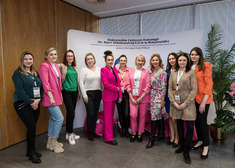 Grupa kobiet pozuje do zdjęcia na tle ścianki Białostockiego Centrum Onkologii