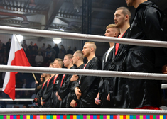 Bokserzy reprezentujący Polskę stoją w rzędzie na ringu przy biało-czerwonej fladze