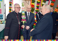 Biskup łomżyński Janusz Stepnowski trzyma w dłoni palmę wielkanocną i stoi w towarzystwie kilku osób