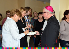 Biskup rozdaje ludziom święceno jajka leżące na talerzu