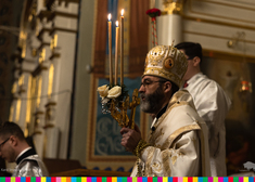 Abp Jakub trzyma w dłoni świecznik z trzema długimi świecami oraz krzyż