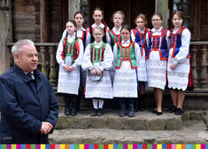 dziewczynki w strojach ludowych stoją przed wejściem do budynku, obok nich stoi wicemarszałek Marek Olbryś 