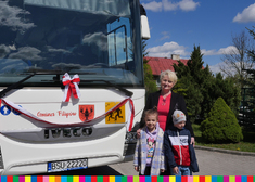 Członek zarządu województwa Wiesława Burnos z dwójka dzieci pozuje do zdjęcia przy autokarze.