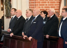 Mężczyźni stoją w ławach podczas mszy św.
