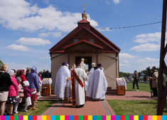 Duchowni przed cerkwią, wokół stoją wierni.