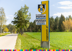 Szyld z herbem gminy Puńsk z tablicami w dwóch językach