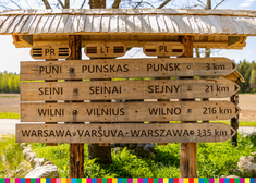 Drewniany drogowskaz z nazwami miejscowości zapisanymi w dwóch językach