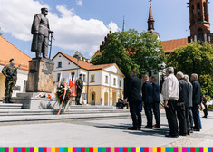 Mężczyźni stoją przed pomnikiem marszałka Józefa Piłsudskiego