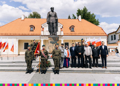 Poczet sztandarowy wojska oraz grupa osób stoi pod pomnikiem ustawiona do zdjęcia
