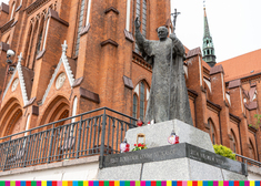 Pomnik św. Jana Pawła II stojący na murze przed białostocką archikatedrą