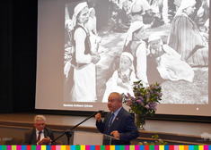 Wicemarszałek Marek Olbryś przy mównicy, za nim widoczne jest czarno-białe zdjęcie na slajdzie