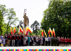 Duża grupa osób stoi pod pomnikiem