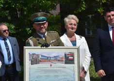 Mundurowy oraz Wiesława Burnos, członek zarządu stoją za plakatem
