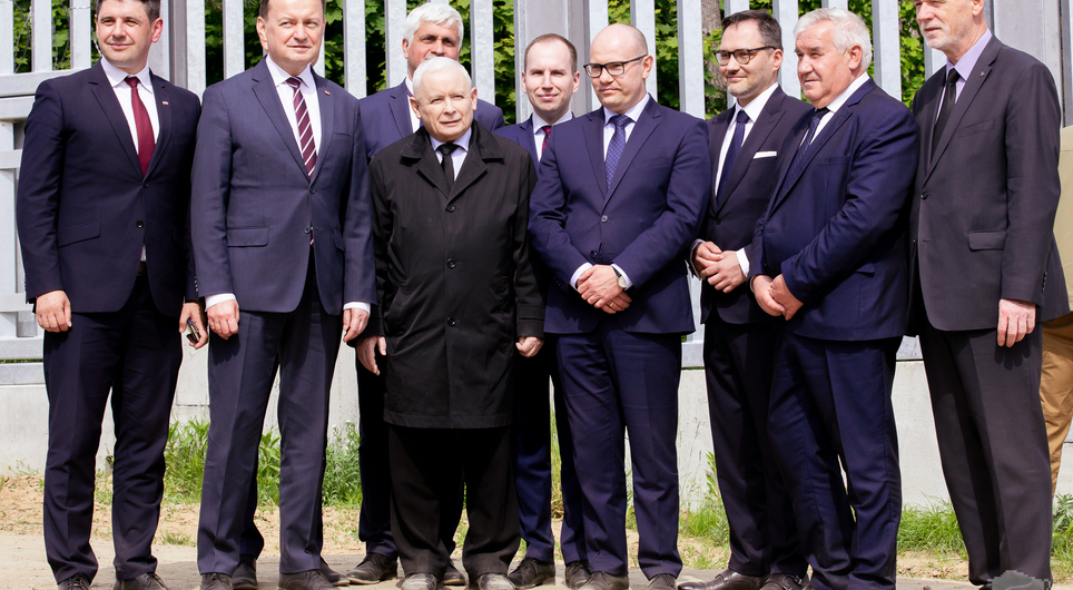 Politycy Prawa i Sprawiedliwości stoją z prezesem Jarosławem Kaczyńskim przy zaporze granicznej