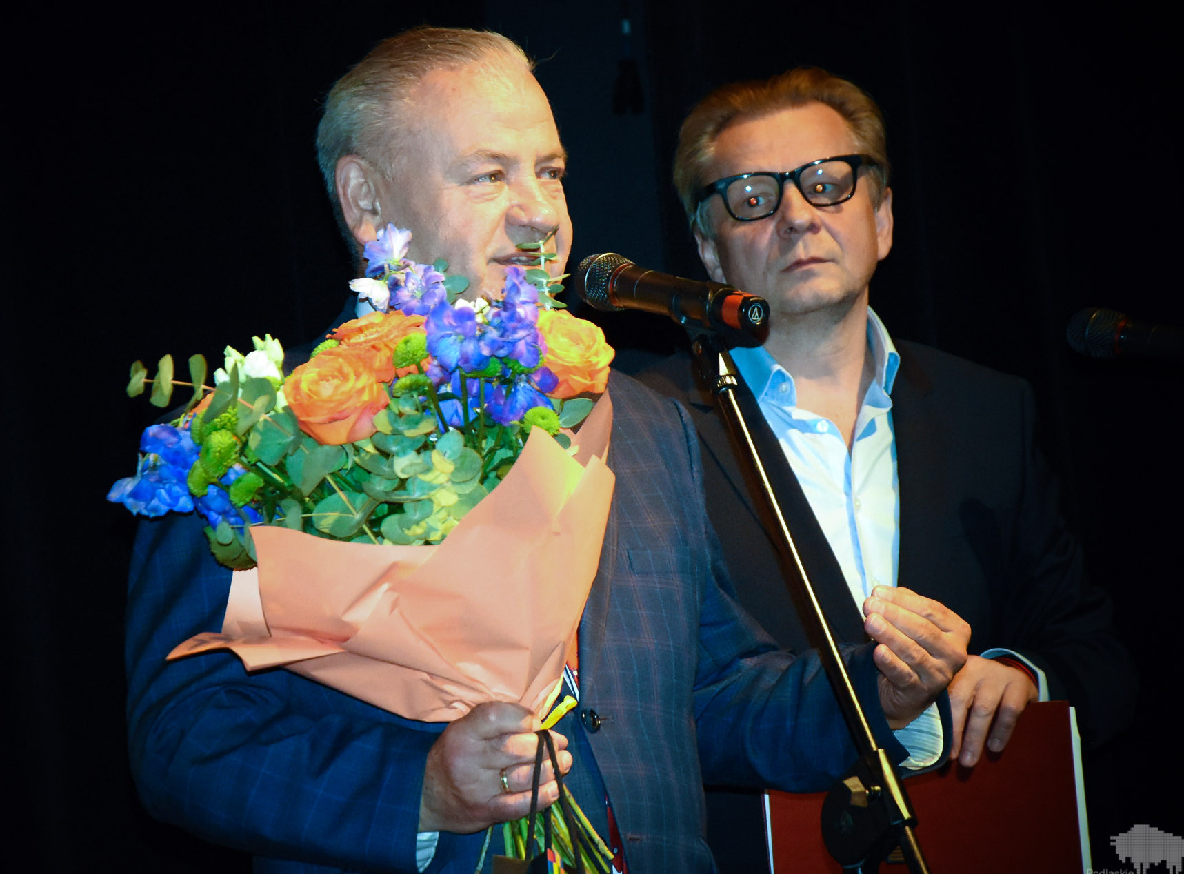 Wicemarszałek Marek Olbryś trzyma bukiet z kwiatami i przemawia przez mikrofon