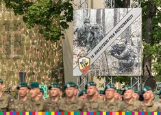 Baner z żołnierzami 18. Białostockiego Pułku rozpoznawczego, poniżej stoją mundurowi