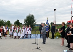 Wicemarszałek Marek Olbryś przemawia przy ludziach ubranych w strojach ludowych i mundurach OSP