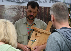 Mężczyzna trzyma drewniany karmnik dla ptaków.