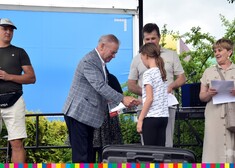 wicemarszałek Marek Olbryś wręcza nagrodę dziecku, stoją na scenie 