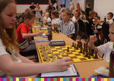 Dzieci grają w szachy i zapisują ruchy swoich figur na szachownicy