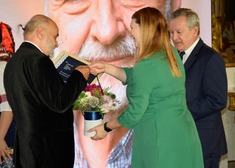 Kobieta wręcza nagrodę Wojciechowi Kowalczukowi