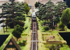 Makieta przedstawiająca pociąg jadący torami kolejowymi przez las