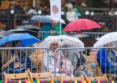 Ludzie pod parasolami.