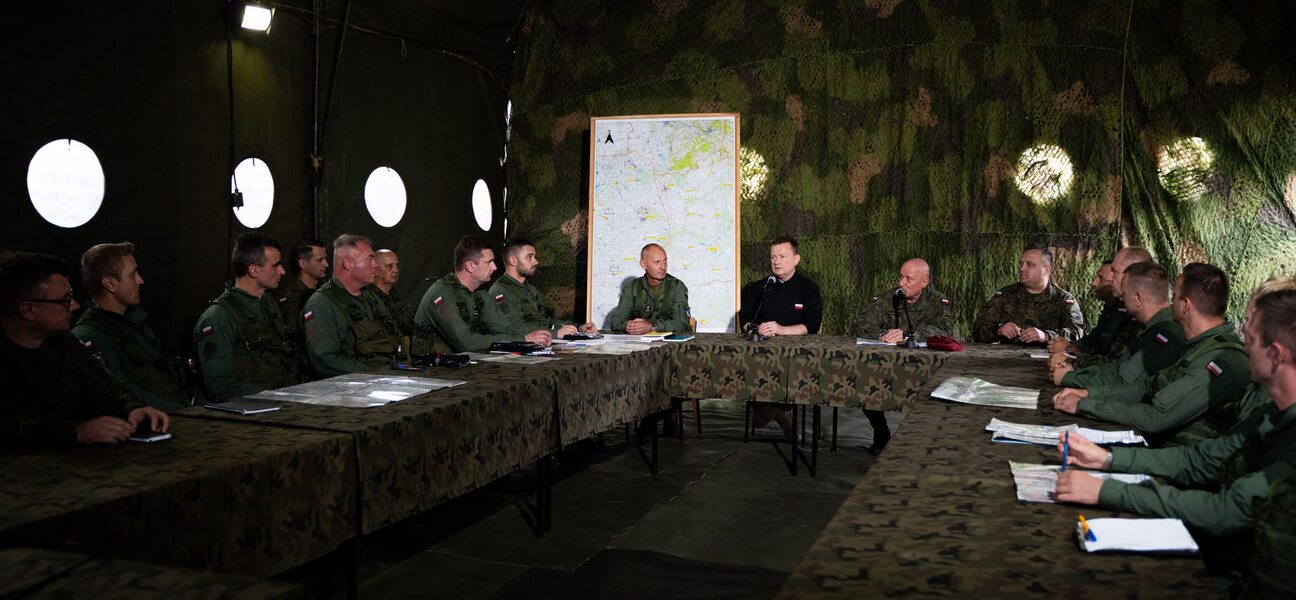 Kilkunastu żołnierzy i dowódców siedzi przy stole. Wśród nich minister.