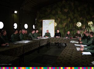 Kilkunastu żołnierzy i dowódców siedzi przy stole. Wśród nich minister.