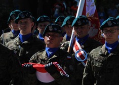 Grupa żołnierzy, jeden trzyma sztandar