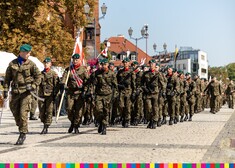 Zołnierze maszerują, jeden niesie sztandar