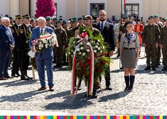 Żołnierz niesie wieniec, za nim kilka osób