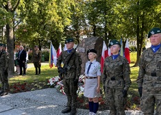 Pomnik i  trójka młodzieży w mundurach