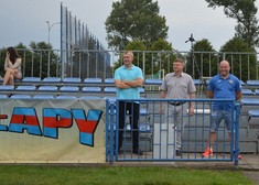 trzech mężczyzn za barierką na stadionie 