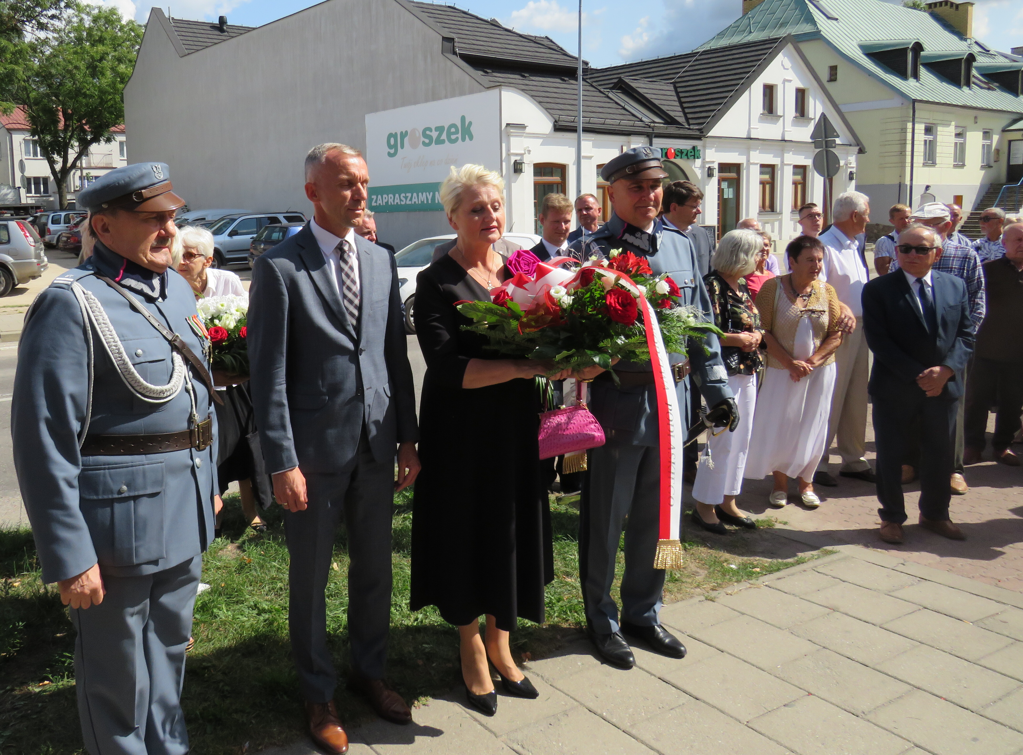 grupa osób podczas składania kwiatów, wśród nich członek zarządu, Wiesława Burnos