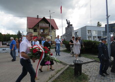 grupa osób podczas składania kwiatów pod pomnikiem 