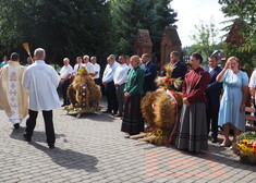 Ksiądz święci wieńce, ludzie stoją w szeregu