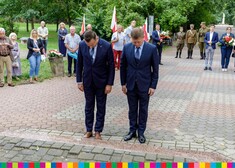 Marek Malinowski i Henry Dębowski przed pomnikiem. Pochylają głowy.