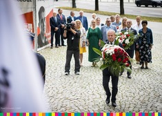 Mężczyzna niosący w kierunku pomnika kwiaty