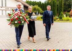 Bohdan Paszkowski i Marek Malinowski trzymają znicz i kwiaty