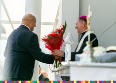 Mężczyzna podaje kwiaty arcybiskupowi