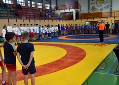 Duża grupa zawodników zebrana w sali gimnastycznej