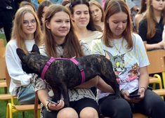 uczestniczka wydarzenia siedzi z psem na kolanach