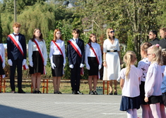 Uczniowie stoją z szarfami biało-czerwonymi stoją w szeregu