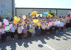 Dzieci stoją na placu z kolorowymi balonami
