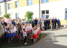 Politycy, samorządowcy wraz z licznie zgromadzonymi przedszkolakami stoją na placu przy budynku