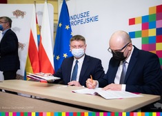 marszałek Artur Kosicki oraz członek zarządu Marek Malinowski siedzą przy stole i podpisują umowy